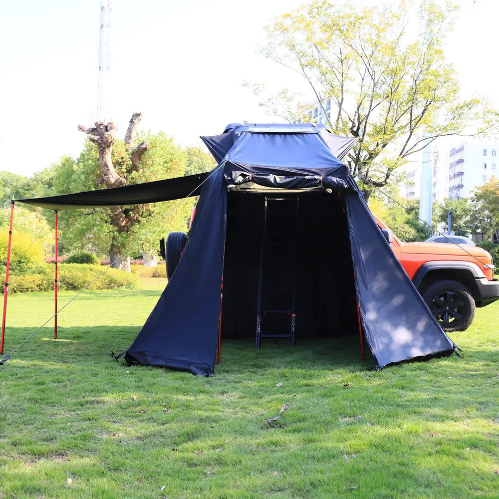 Blue tent attached to a vehicle in a park setting with trees and grass.
