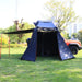 Blue tent attached to a vehicle in a park setting with trees and grass.