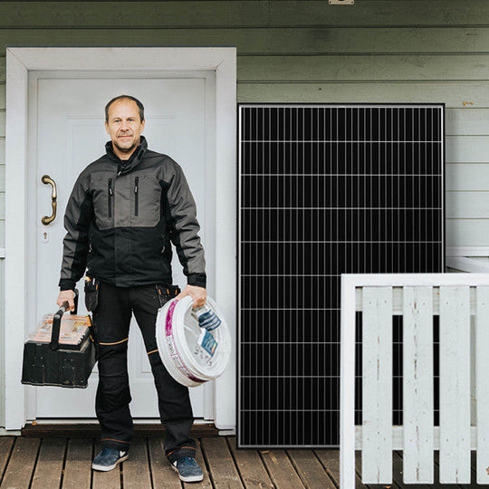 Man holding tools in front of a house with a solar panel on the wall.