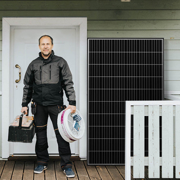 Man holding tools in front of a house with a solar panel on the wall.